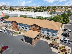 A multi-story hotel with a parking lot, a covered outdoor area, and a view of the surrounding neighborhood.