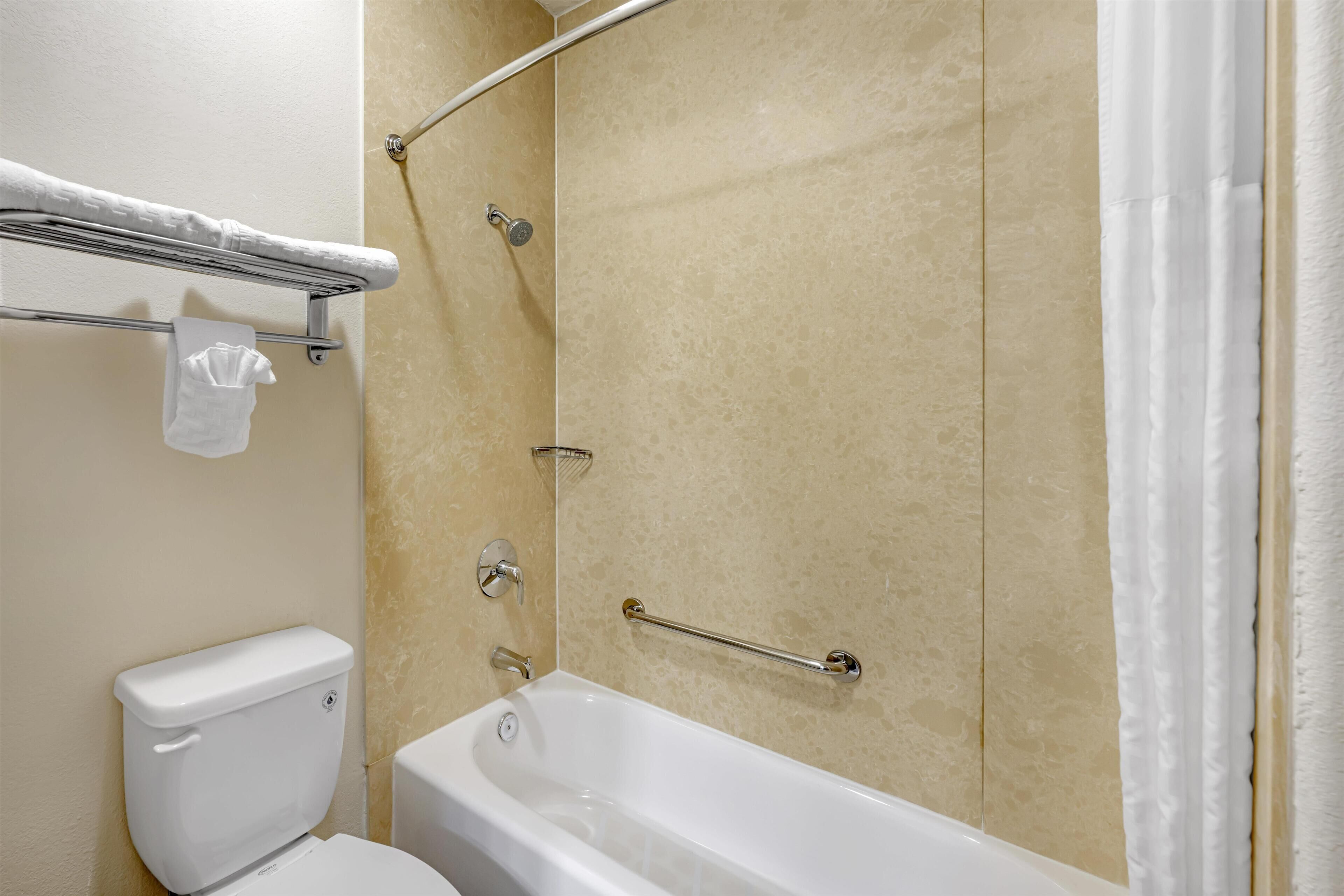 A bathroom with a bathtub, a toilet, and a shower area.