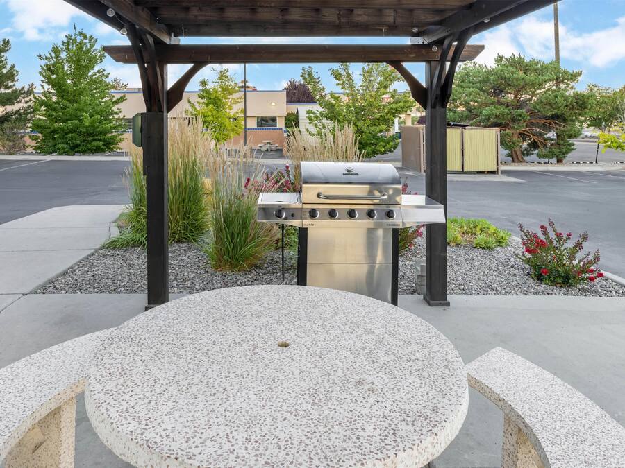 An outdoor patio with a round table and a barbecue grill.