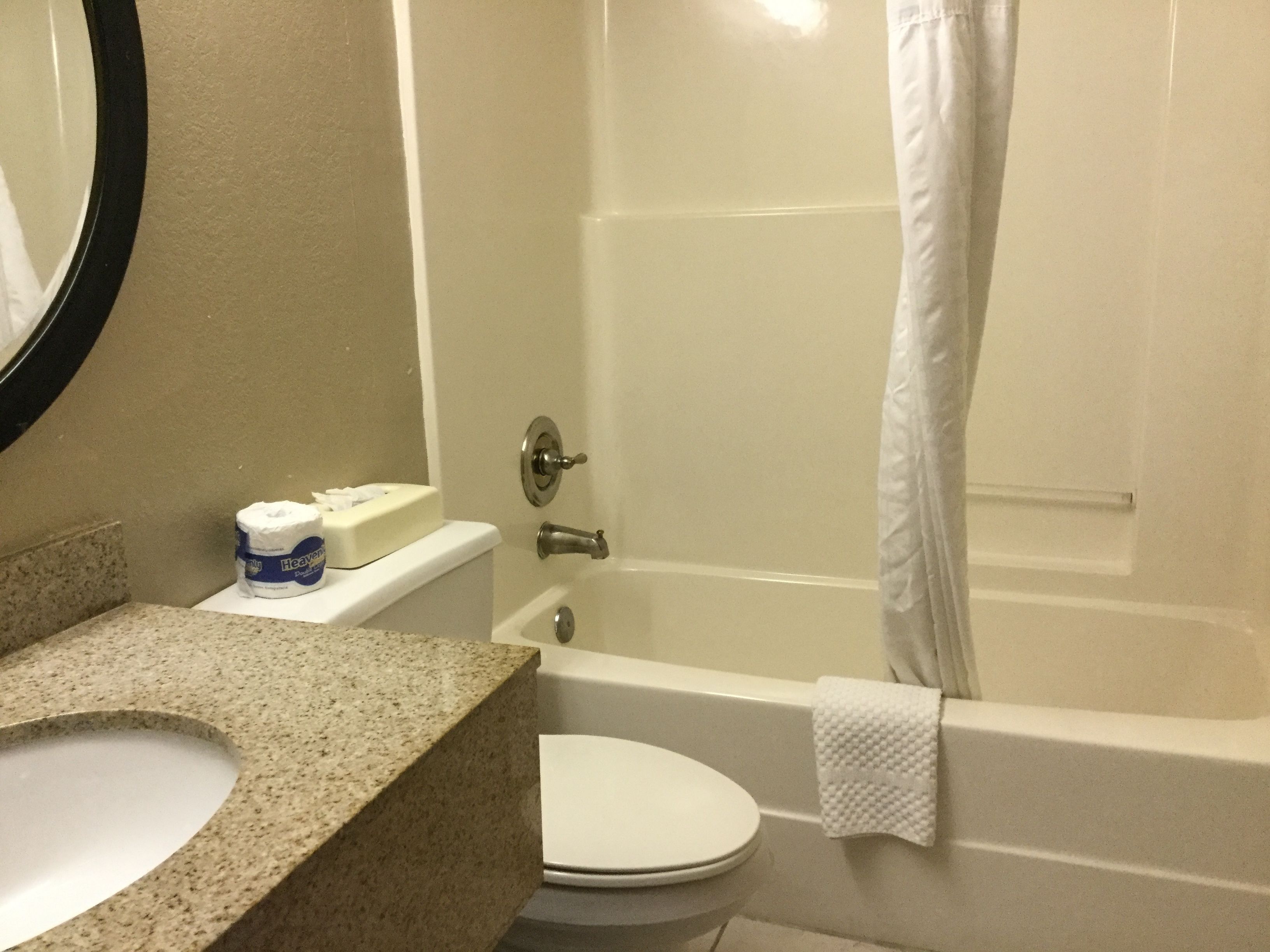 A bathroom with a granite countertop, toilet, and bathtub.