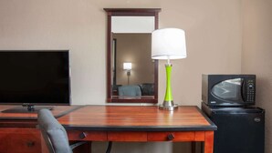 A hotel room with a wooden desk, a television, a green lamp, and a microwave. - Super 8 by Wyndham Waycross GA (Waycross)