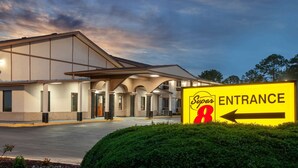 A Super 8 hotel entrance with a clear sign indicating the direction to the entrance. - Super 8 by Wyndham Waycross GA (Waycross)