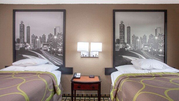 A hotel room with two beds, a nightstand with a phone, and two wall-mounted lamps. - Super 8 by Wyndham Waycross GA (Waycross)