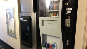 A vending machine with a push button and a coin dispenser, located in a hallway with a patterned carpet. - Super 8 by Wyndham Waycross GA (Waycross)