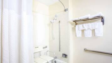 Un baño con ducha, barra de apoyo, toallero con toallas y un inodoro con asiento elevado.