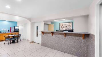 A modern kitchen with a granite countertop, a dining area with a table and chairs, and a blue accent wall.