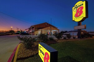 Un motel Super 8 con un letrero grande, un estacionamiento y un edificio de techo inclinado.
