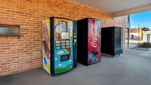 Two vending machines, one with a colorful design and the other with a Coca-Cola logo, against a brick wall. - Super 8 by Wyndham Pleasanton (Pleasanton)