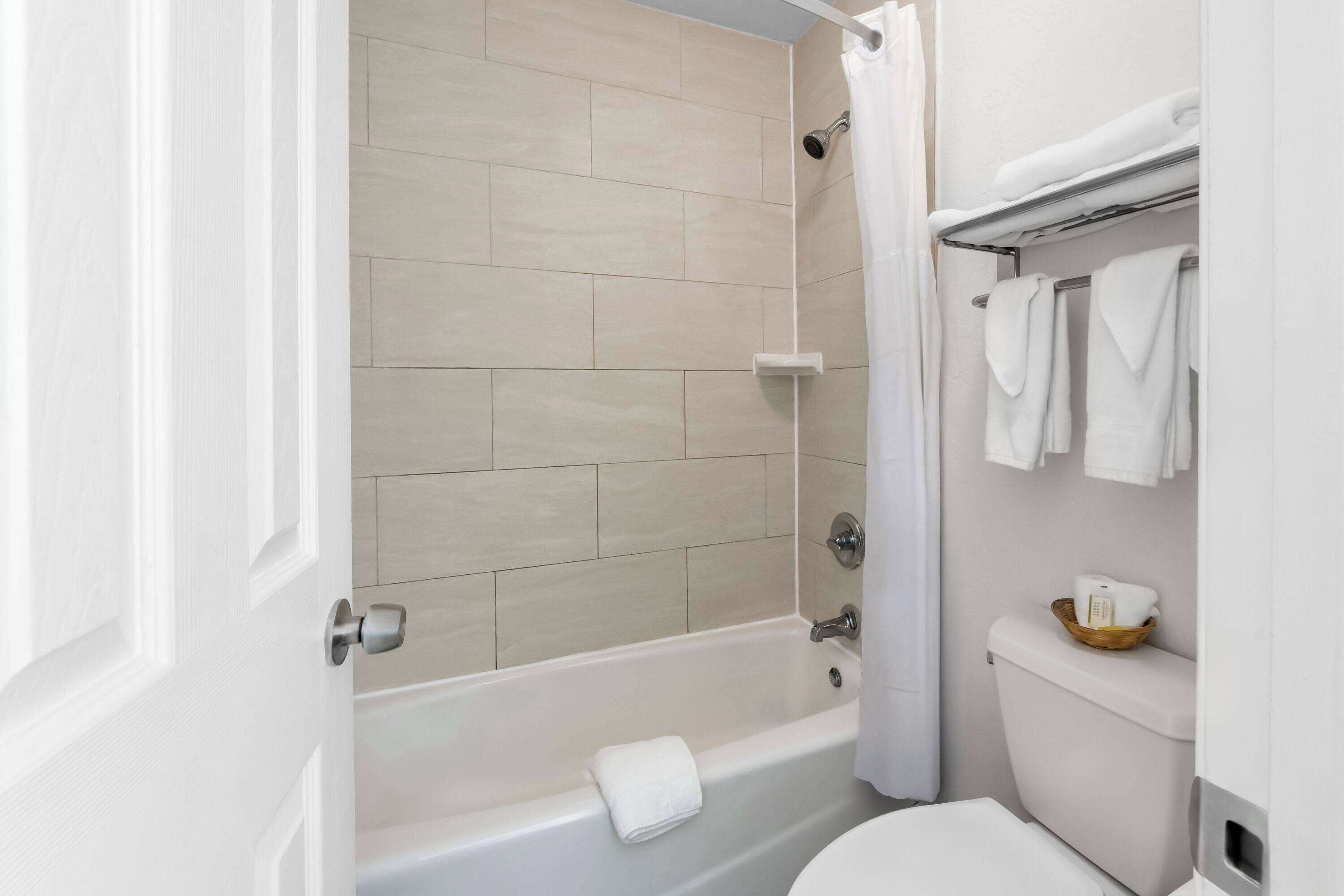 A bathroom with a bathtub, toilet, and a shower curtain.