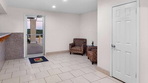 A room with a tiled floor, a door, and two armchairs. - Super 8 by Wyndham Pleasanton (Pleasanton)