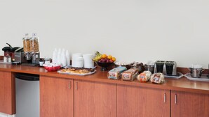 A buffet setup with various food items, including fruits, pastries, and bread, along with disposable cups and a coffee machine. - Super 8 by Wyndham Edmonton/West (Edmonton)