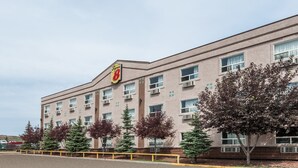 A multi-story building with a prominent '8' logo on the facade, surrounded by trees and a yellow safety barrier. - Super 8 by Wyndham Edmonton/West (Edmonton)