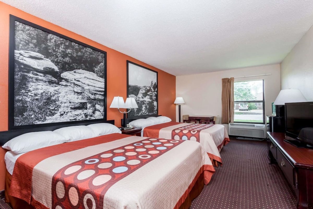 Une chambre d’hôtel avec deux lits, une télévision, un bureau et une fenêtre.