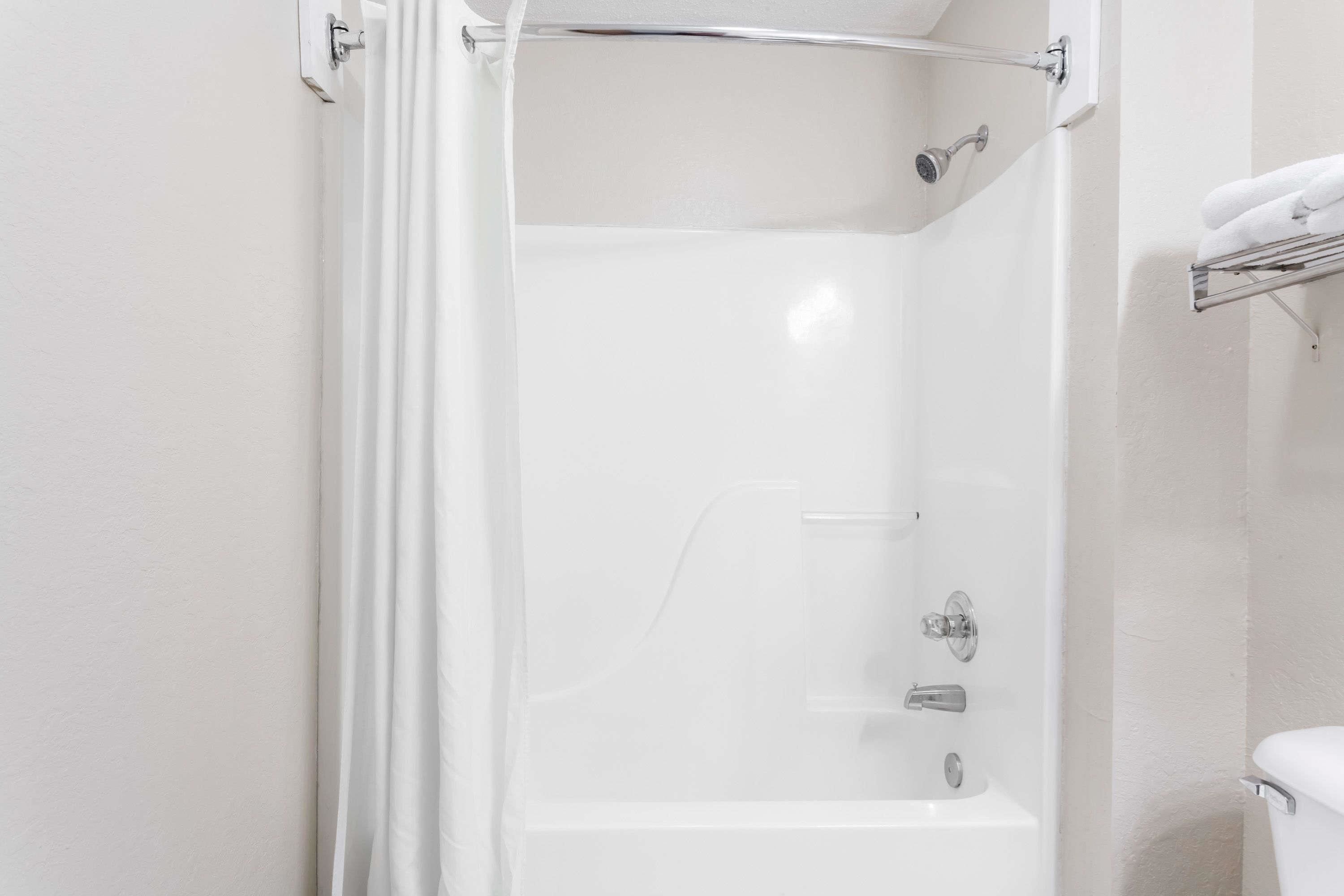 Une salle de bain blanche avec une douche à parois de verre, des toilettes blanches et un porte-serviettes.