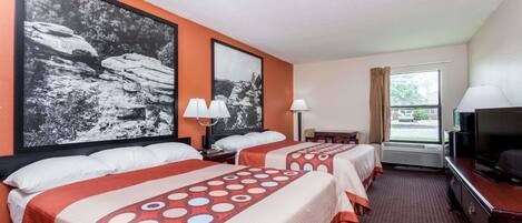 A hotel room with two beds, a TV, and a window with curtains.