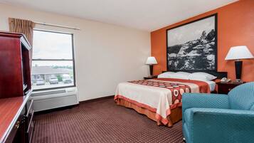 A hotel room with a bed, two bedside lamps, a large window, a desk, and a chair.