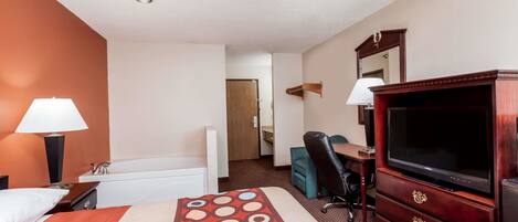 A hotel room with a bed, a desk, a chair, a television, a dresser, and a mirror.