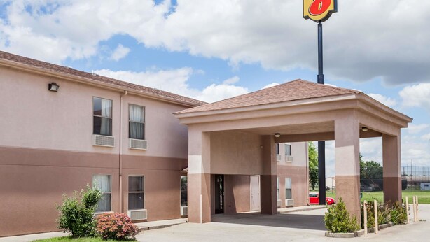 Ein Super 8 Hotel mit überdachter Einfahrt, Parkplatz und blauem Himmel.