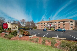 A hotel with a parking lot, a building entrance, and a sign for the Red Carpet Inn.