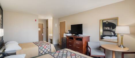 A hotel room with two beds, a TV, a desk with a chair, a lamp, and a painting on the wall.