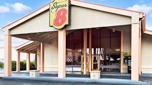 Suuri Super 8 -hotelli, jossa on suuri kyltti, katettu sisäänkäynti ja myyntiautomaatti.
