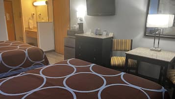 A hotel room with two beds, a desk, a chair, a television, and a mirror.