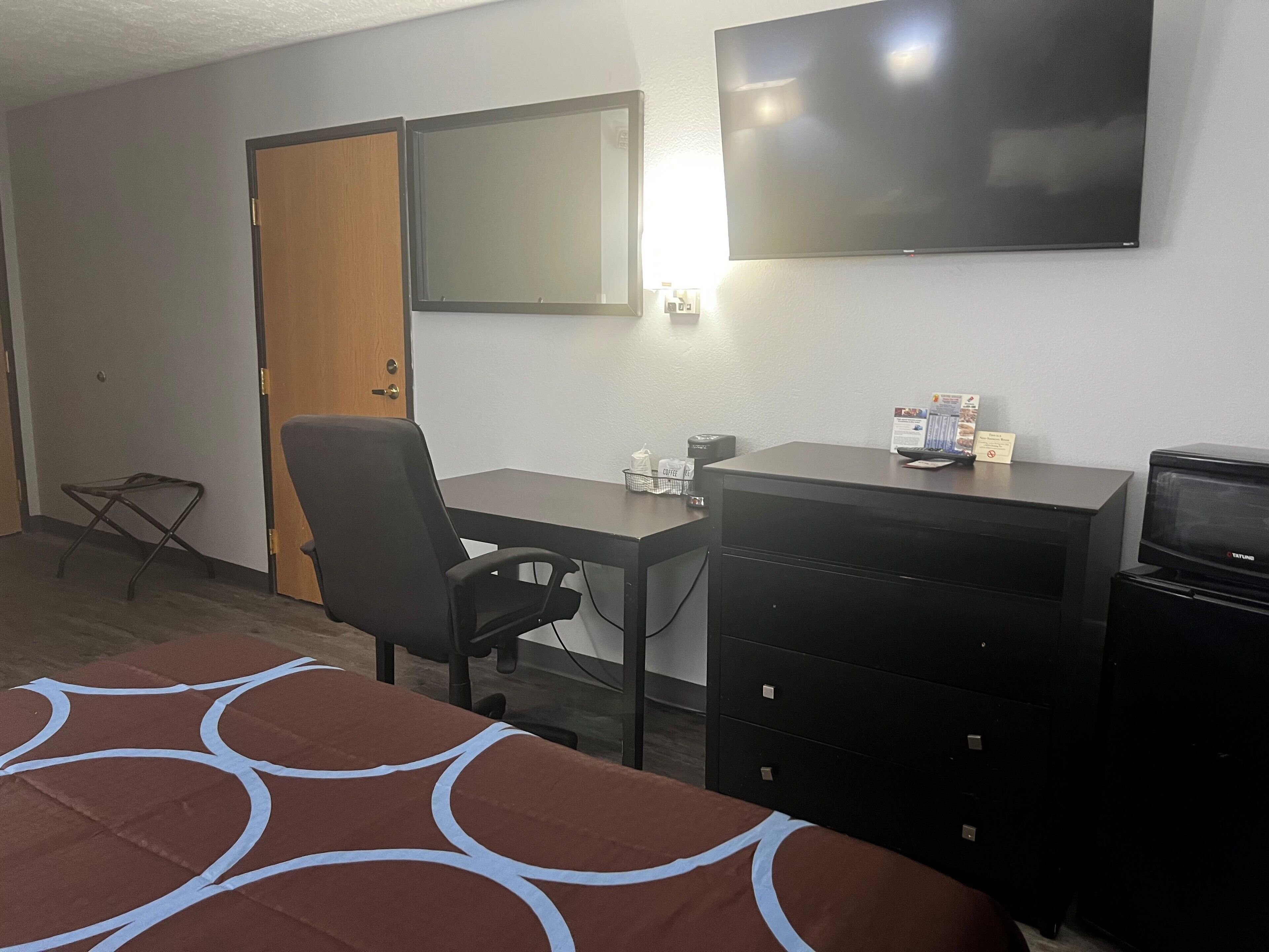 Ein Hotelzimmer mit Bett, Schreibtisch, Sessel, Fernseher und Kommode.