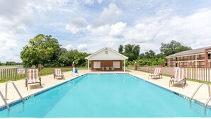 Piscina retangular com um pequeno edifício ao fundo.