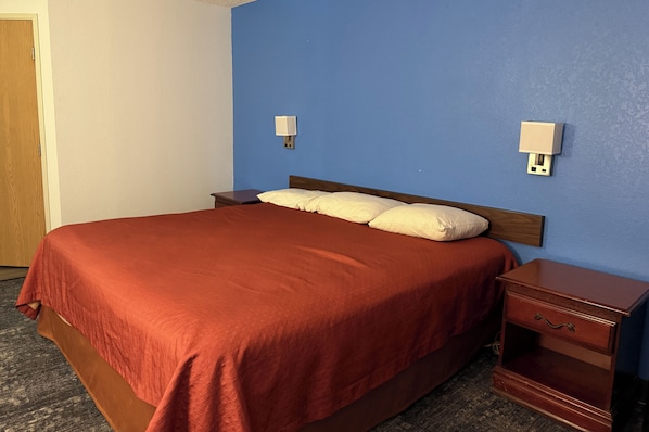 Une chambre d’hôtel avec un grand lit, deux tables de chevet et une petite table de nuit.