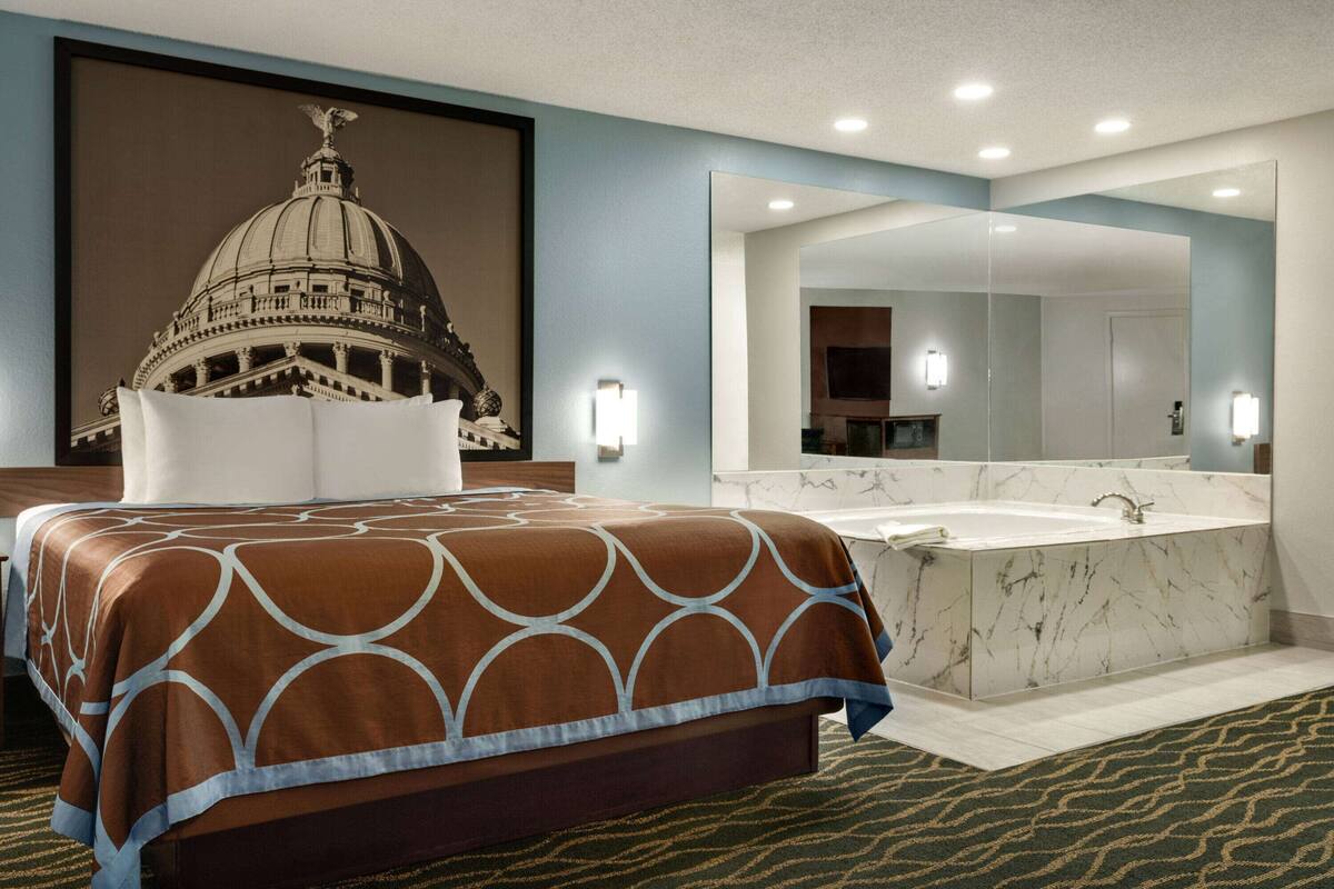 Een hotelkamer met een groot bed, een badkamer met een marmeren wastafel en een grote spiegel.
