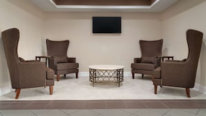 A room with two brown upholstered chairs, a round table with a metal base, and a flat-screen TV mounted on the wall. - Super 8 by Wyndham Pearl/Jackson Airport (Pearl)