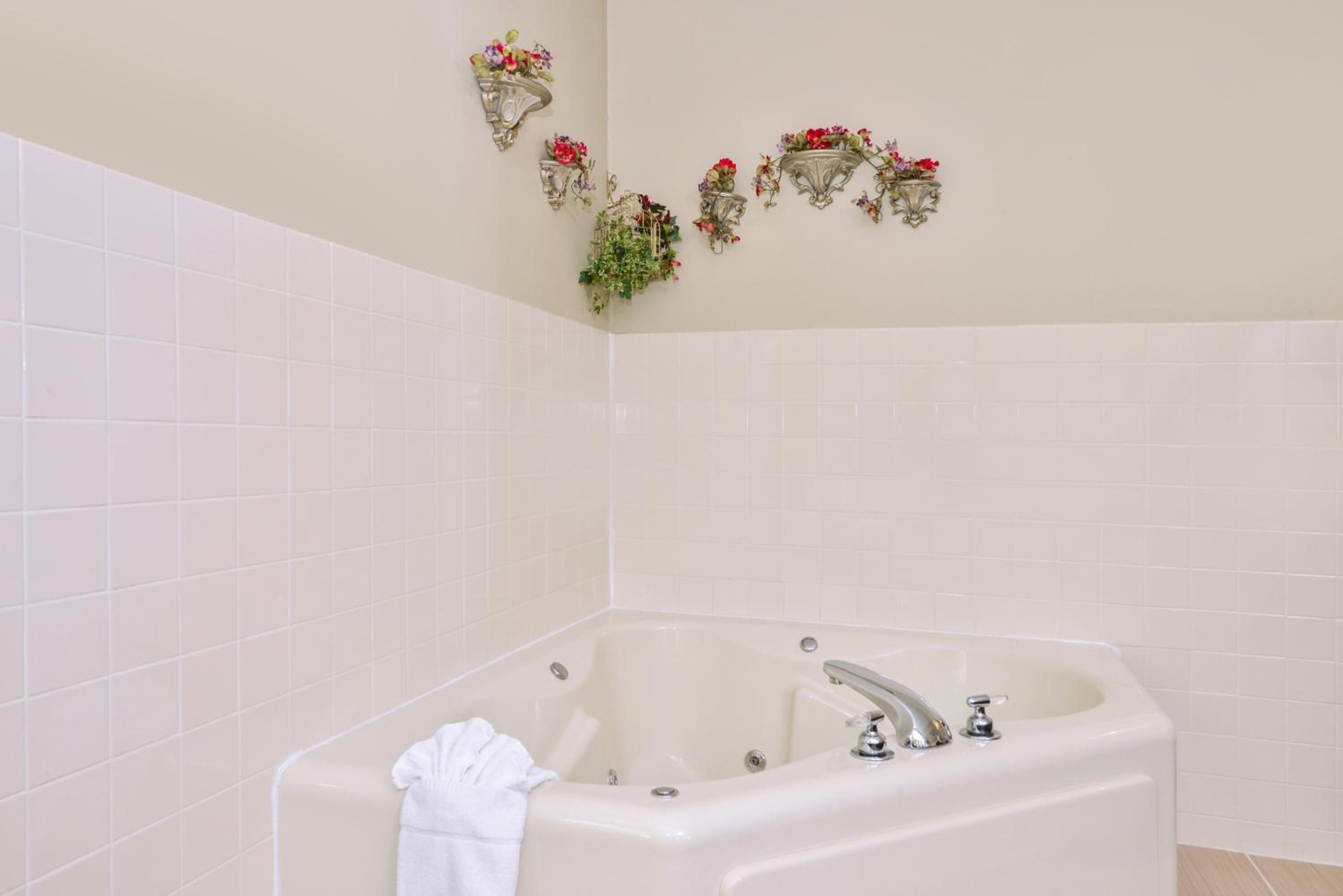 A bathroom with a freestanding bathtub, white tiled walls, and wall-mounted sconces with floral decorations.