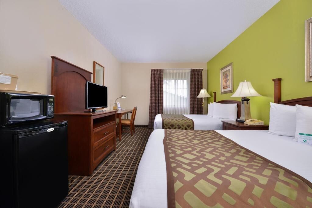 A hotel room with a bed, a desk with a television, a microwave, a lamp, and a telephone.