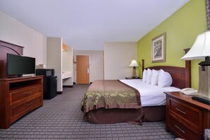 A hotel room with a bed, a television, a desk, and a lamp.