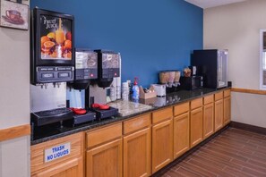 A self-service beverage station with fruit juice dispensers and a trash bin labeled "TRASH NO LIQUIDS".