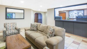 Uma sala de estar com uma poltrona estampada, um sofá bege e uma mesa de centro de madeira.
