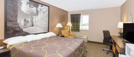 A hotel room with a large bed, two bedside lamps, a desk with a computer, and a television.