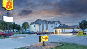 Um motel com um grande letreiro 'Super 8', um estacionamento e um edifício com teto plano.