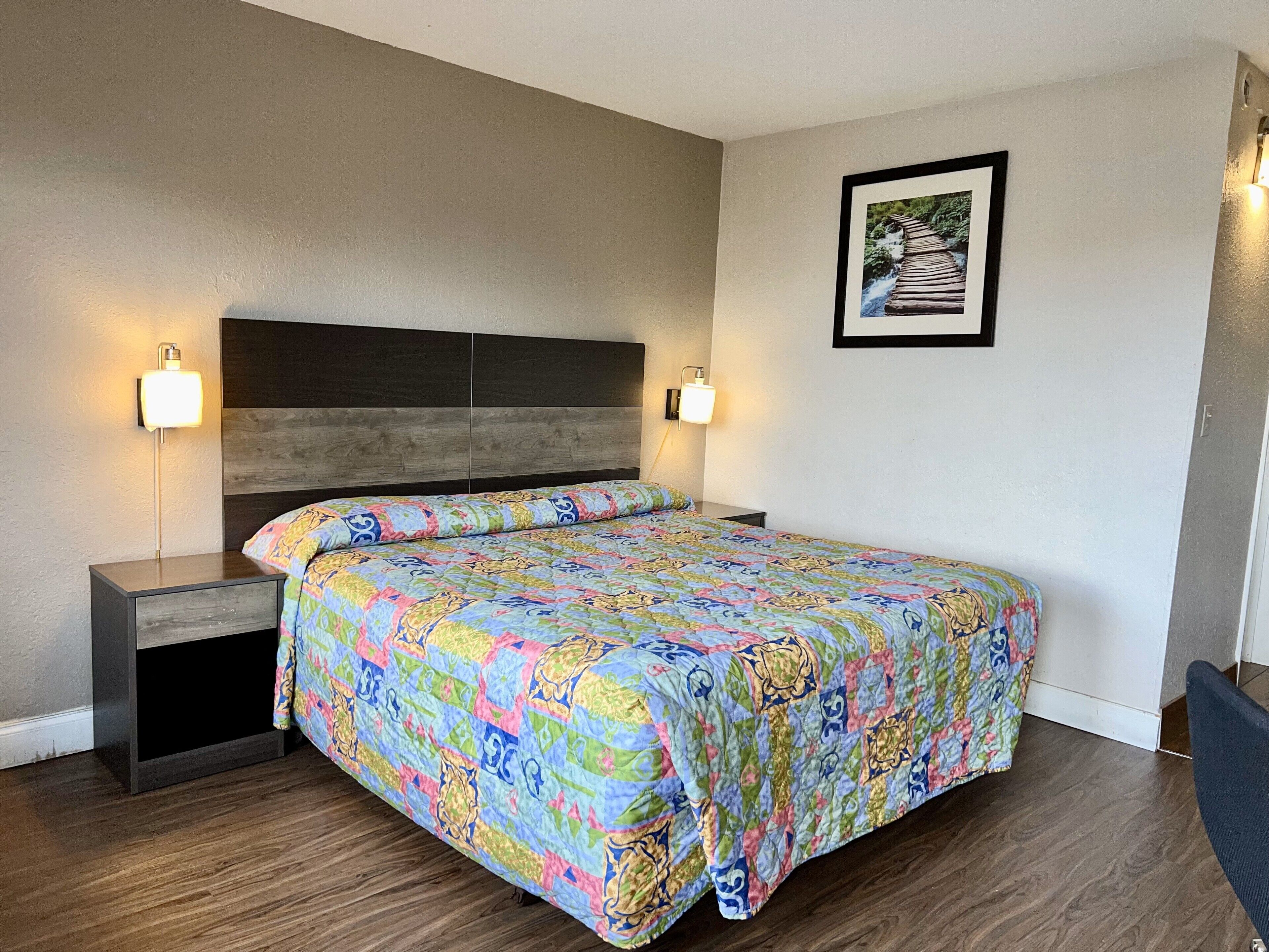 Un dormitorio con una cama grande, dos mesitas de noche y un cabecero.