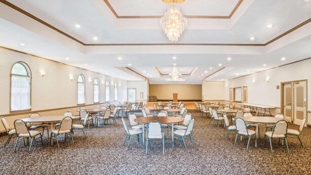 A large conference room with multiple tables and chairs, a chandelier, and a carpeted floor. - Super 8 by Wyndham Brooklyn (Brooklyn)