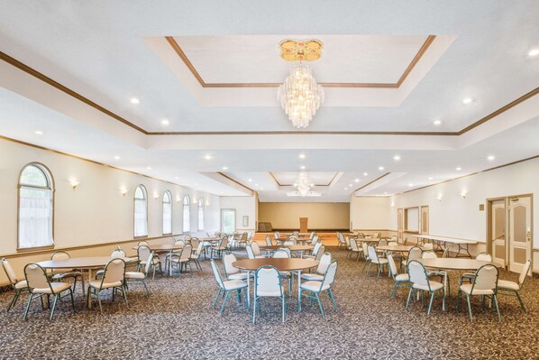 A large conference room with multiple tables and chairs, a chandelier, and a carpeted floor. - Super 8 by Wyndham Brooklyn (Brooklyn)