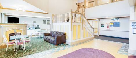 A spacious lobby with a fireplace, seating area, and a staircase leading to an upper floor.