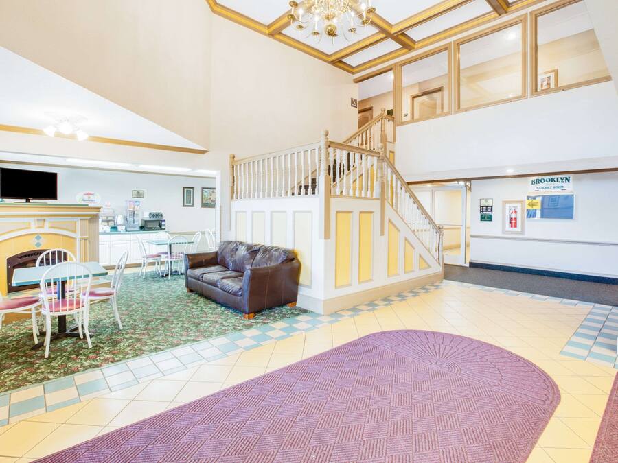 A spacious lobby with a fireplace, seating area, and a staircase leading to an upper floor.