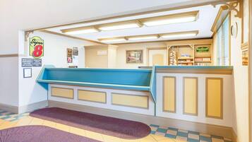 A hotel reception area with a check-in counter, a sign for 'Super 8', and a 'Backwall Cafe' sign.