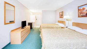 Habitación de hotel con dos camas, televisión, cómoda y puerta de baño.