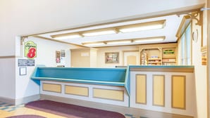 A hotel reception area with a check-in counter, a sign for 'Super 8', and a 'Backwall' sign indicating a back area. - Super 8 by Wyndham Brooklyn (Brooklyn)