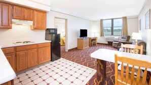 Una habitación de hotel compacta con kitchenette, televisión de pantalla plana, sofá y zona de comedor.