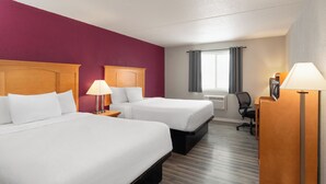A hotel room with two beds, a desk, a chair, and a window with curtains. - Sauk River Inn & Suites, a Travelodge by Wyndham (Sauk Centre)