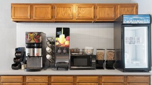 A kitchen with wooden cabinets, a coffee maker, a microwave, a blender, and a refrigerator. - Sauk River Inn & Suites, a Travelodge by Wyndham (Sauk Centre)