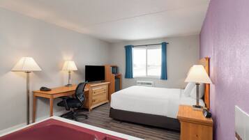 A hotel room with a bed, desk, chair, TV, and a bathtub.